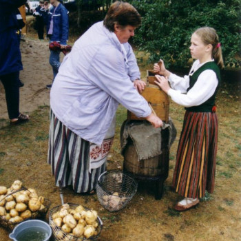 ''Pļaujas svētki''. Pie muzeja saimes mājas kartupeļus rīvē, no kreisās puses, Lilija Alksne un Ilze Paraņuka. 2002. g. 14. septembrī.
KPNM PLG 1050